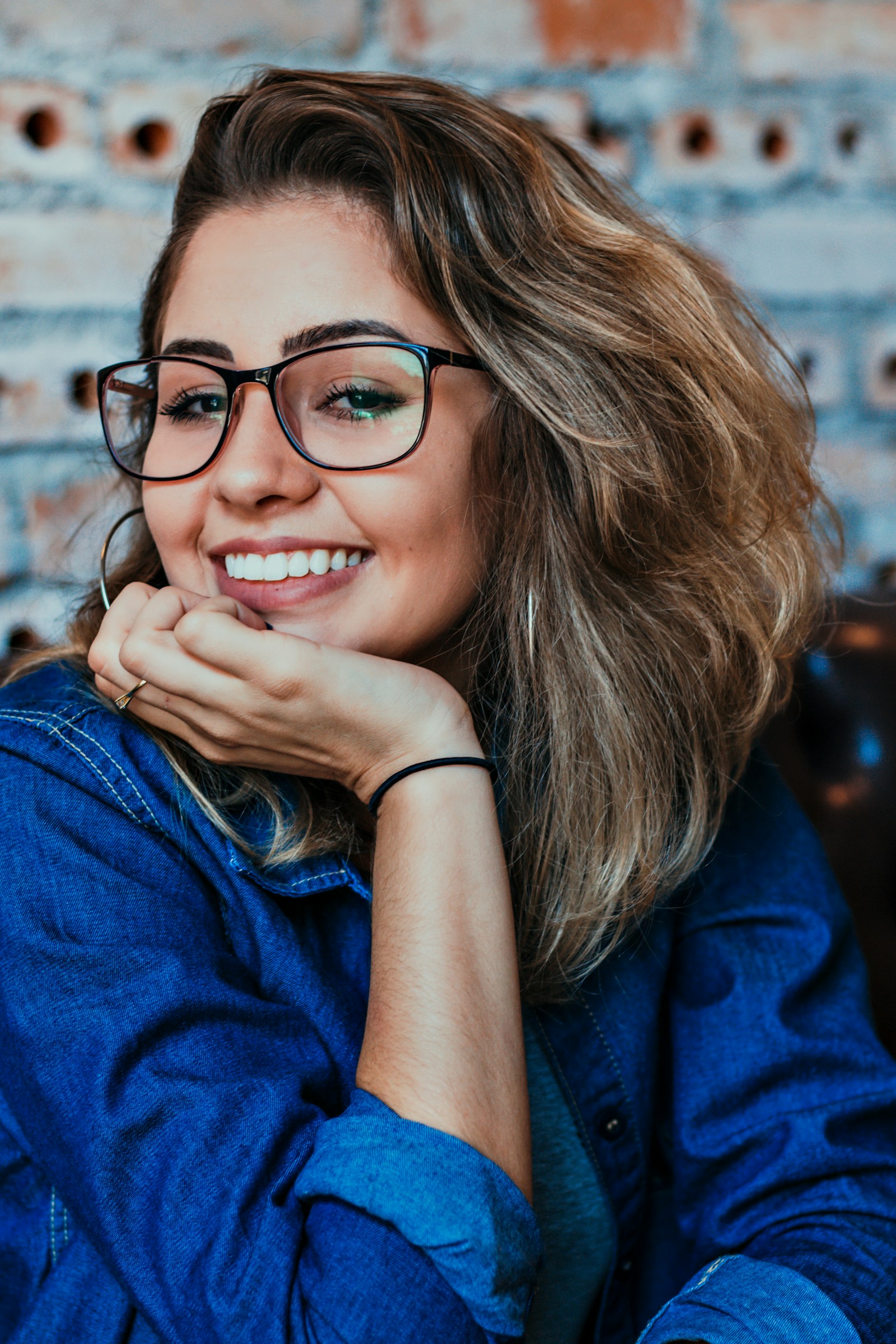 Woman with black-framed glasses smiling brightly
